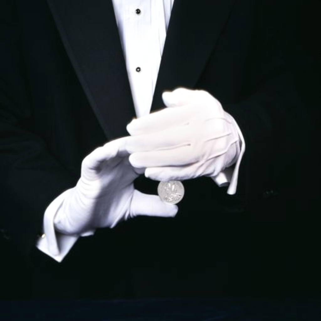 White-gloved hands turning a silver coin in a sleight of hand, illustrating the hidden ownership a nominee arrangement conceals from the Indonesian land register.